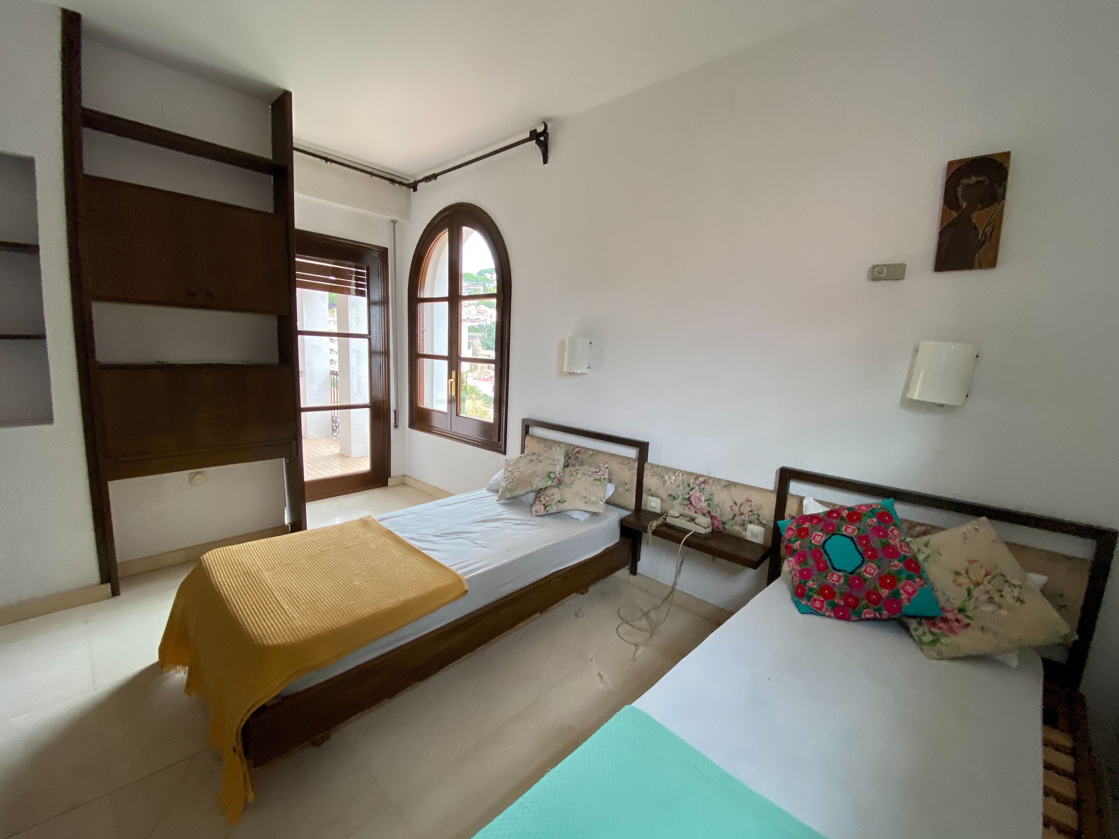 Una habitación con dos camas, una ventana y una puerta.