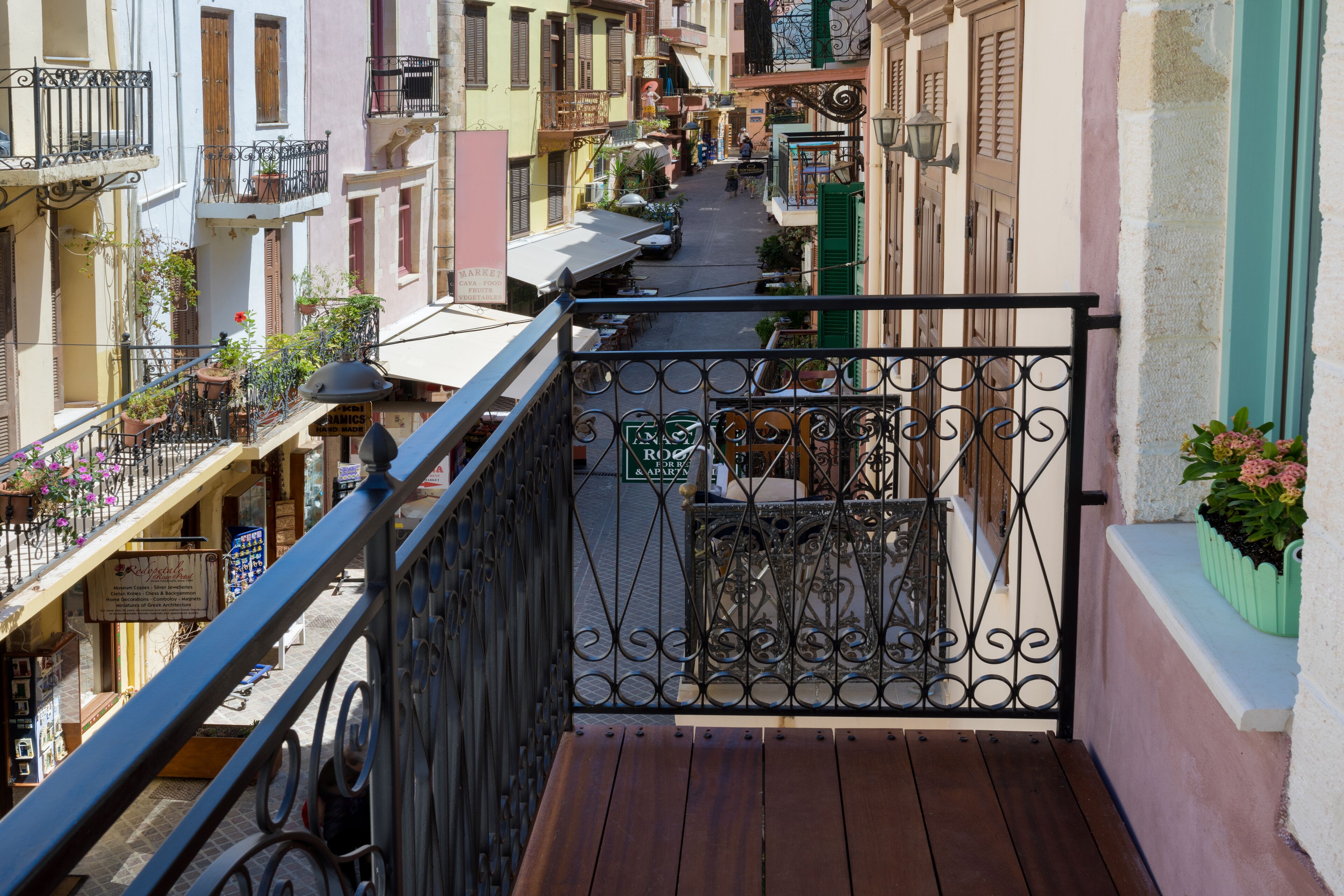 A narrow street with balconies, a wooden deck, and a sign for a restaurant.
