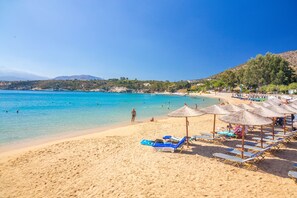 A beach with clear turquoise water, sun loungers, and umbrellas. - Iosifinas Boutique House (Chania)