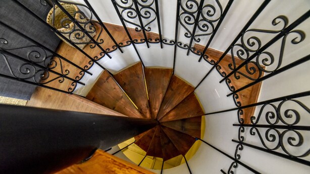 Eine Wendeltreppe mit Holzausstattung und schwarzen schmiedeeisernen Geländern.