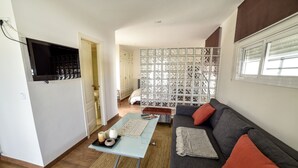 Ein Wohnzimmer mit einer Couch, einem Couchtisch und einem an der Wand befestigten Fernseher.