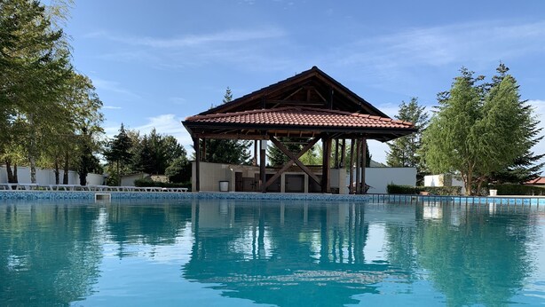A clear swimming pool with a pavilion in the background. - Bultrak- eco village (Balchik)
