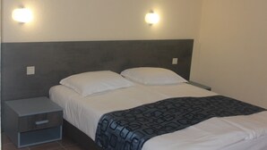 A neatly made bed with a patterned blanket, a bedside table with a drawer, and two wall-mounted light fixtures. - Bultrak- eco village (Balchik)