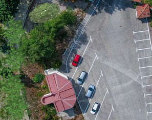 An aerial view of a parking lot with three cars, a red-roofed building, and surrounding greenery. - Bultrak- eco village (Balchik)