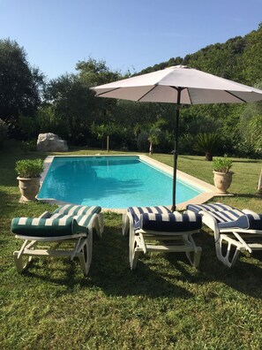 A swimming pool with lounge chairs and an umbrella.