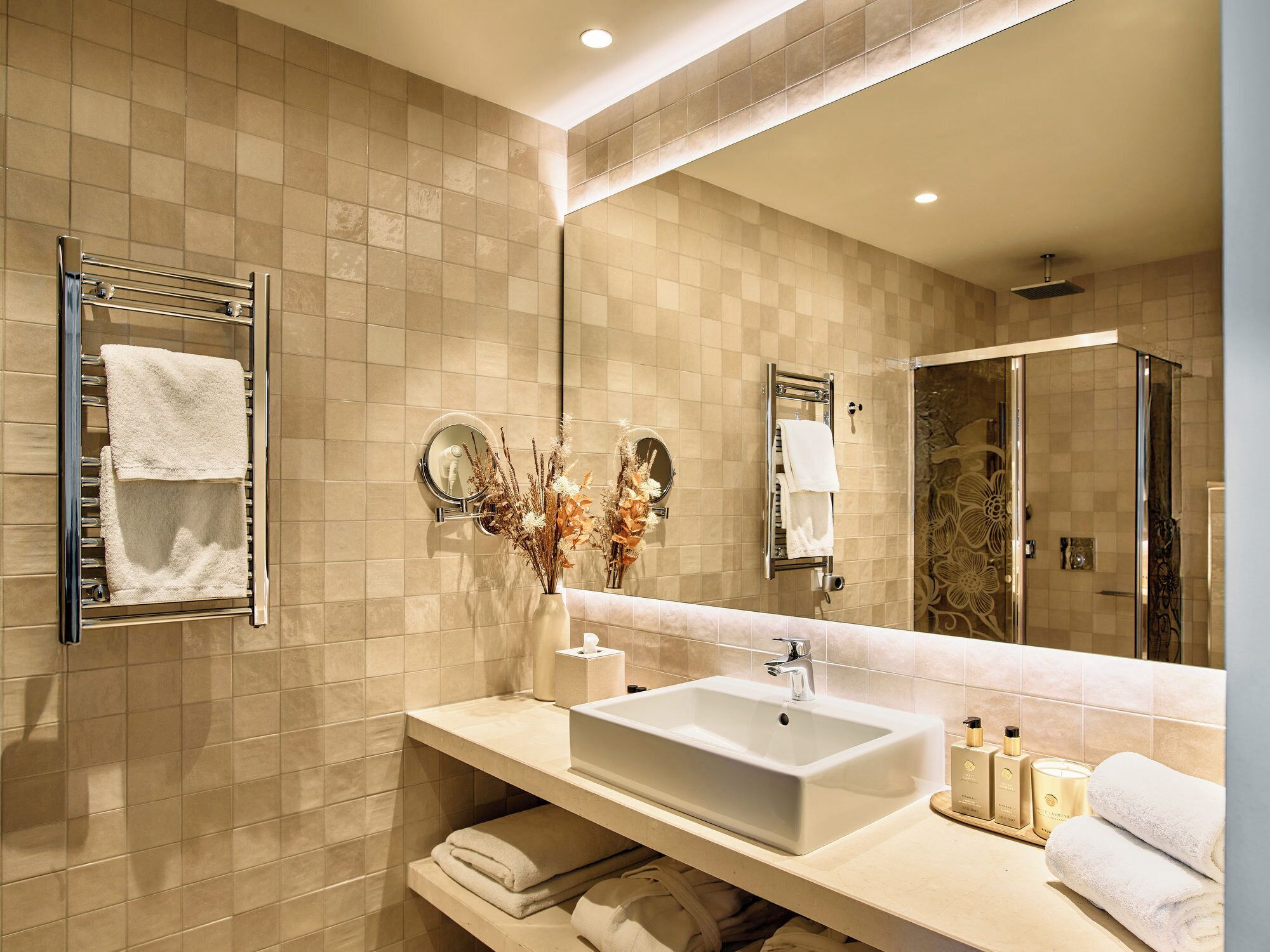 A modern bathroom with a large mirror, a sink, and a shower.