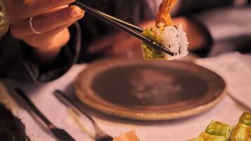 Una persona sosteniendo un trozo de sushi con palillos.
