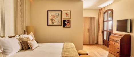 A hotel room with a large bed, a wooden dresser, a television, and artwork on the wall.