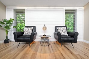 Una habitación con dos sillones negros, una mesita redonda y una planta en maceta.