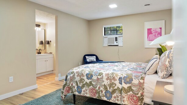 A bedroom with a bed, a dresser, a mirror, a window with blinds, and a wall-mounted air conditioner. - THE BLOSSOM @ DOLLYS DRIVE * Wifi Grill Woods Mtns (Sevierville)