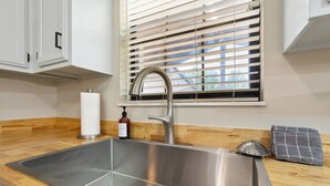 A stainless steel kitchen sink with a modern faucet, a wooden countertop, a window with blinds, and a towel rack. - THE BLOSSOM @ DOLLYS DRIVE * Wifi Grill Woods Mtns (Sevierville)