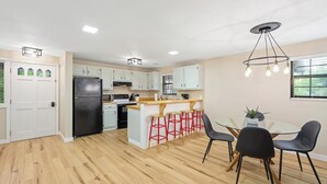 A modern kitchen with white cabinets, a black refrigerator, and a wooden island with stools. - THE BLOSSOM @ DOLLYS DRIVE * Wifi Grill Woods Mtns (Sevierville)