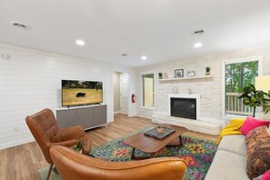 Ein modernes Wohnzimmer mit Kamin, Wandfernseher und einer gemütlichen Sitzecke mit Ledersessel und Sofa.