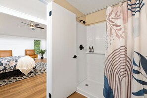 Ein Schlafzimmer mit einem Bett, einem Deckenventilator, einem Fenster und einer Topfpflanze.