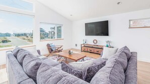 A modern living room with a grey sofa, wooden coffee table, and a TV mounted on the wall.