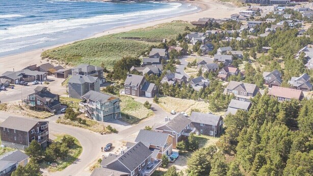 A coastal residential area with houses, a beach, and dunes.