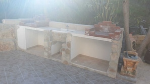 An outdoor kitchen area with stone walls and a sink.