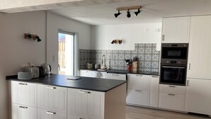 Een moderne keuken met witte kasten, een zwart aanrecht en een ingebouwde oven.