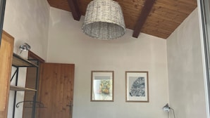 Een slaapkamer met een bed, een bureau, een stoel, een houten garderobe en twee ingelijste foto's aan de muur.