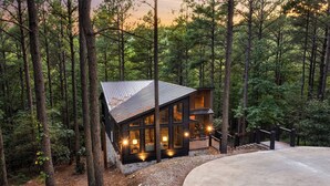 Een chalet met een metalen dak, grote ramen en een terras.