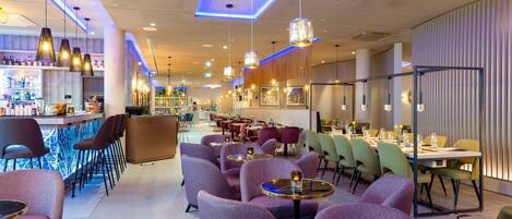 Un restaurant moderne avec des chaises à revêtement violet, des tables rondes et des luminaires suspendus.