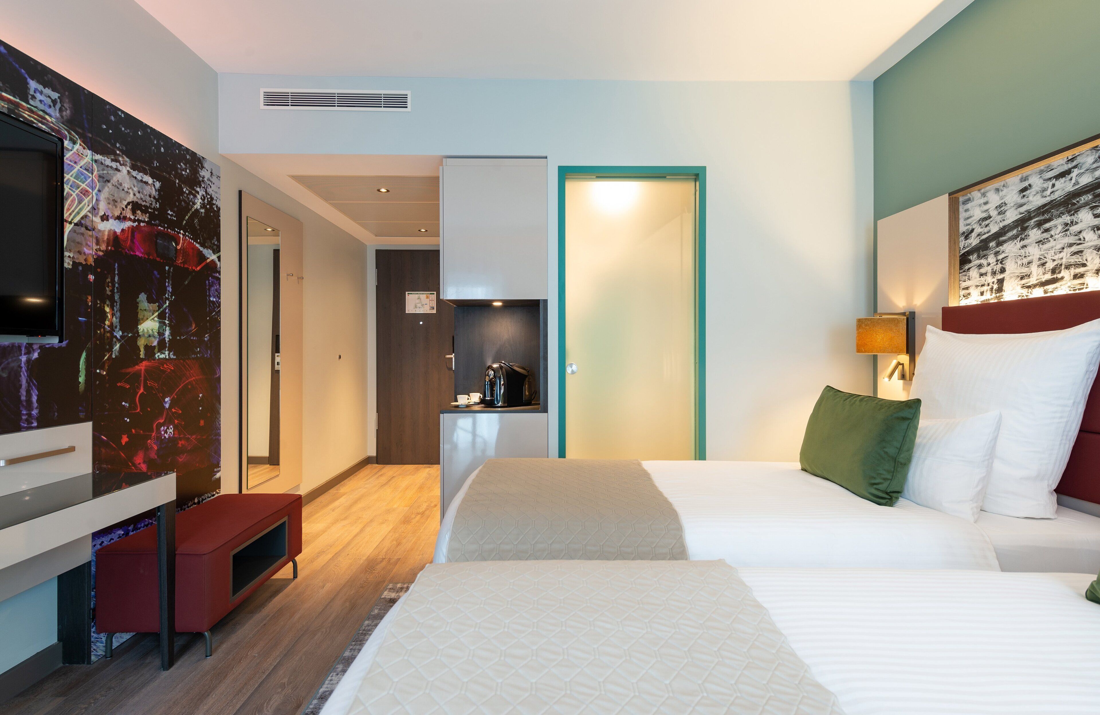 Una habitación de hotel moderna con una cama grande, televisión, escritorio y kitchenette.