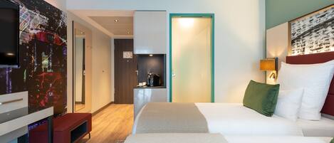 Una habitación de hotel moderna con una cama grande, televisión, escritorio y kitchenette.
