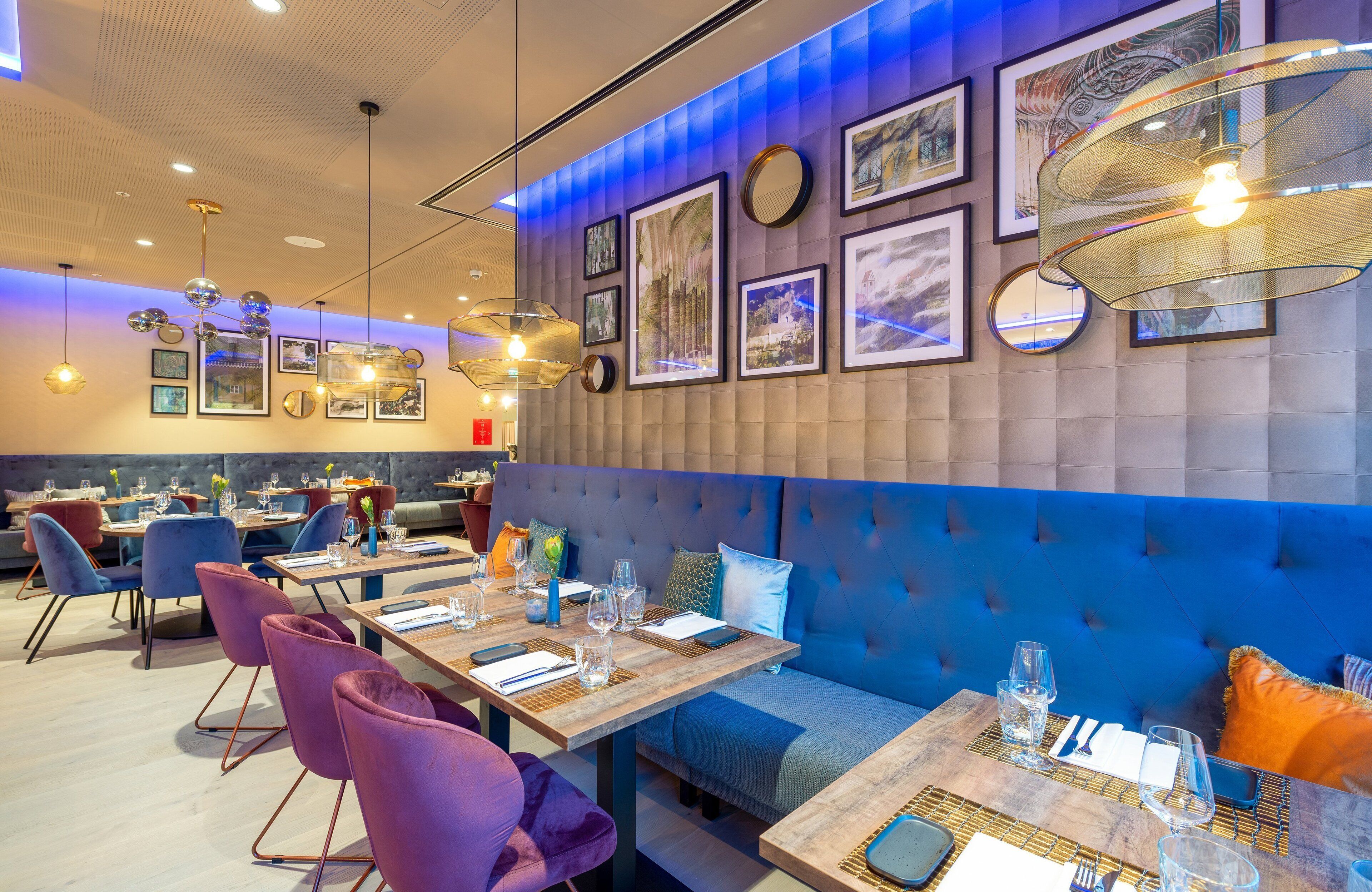 A restaurant with wooden tables, purple chairs, and blue cushioned seating.