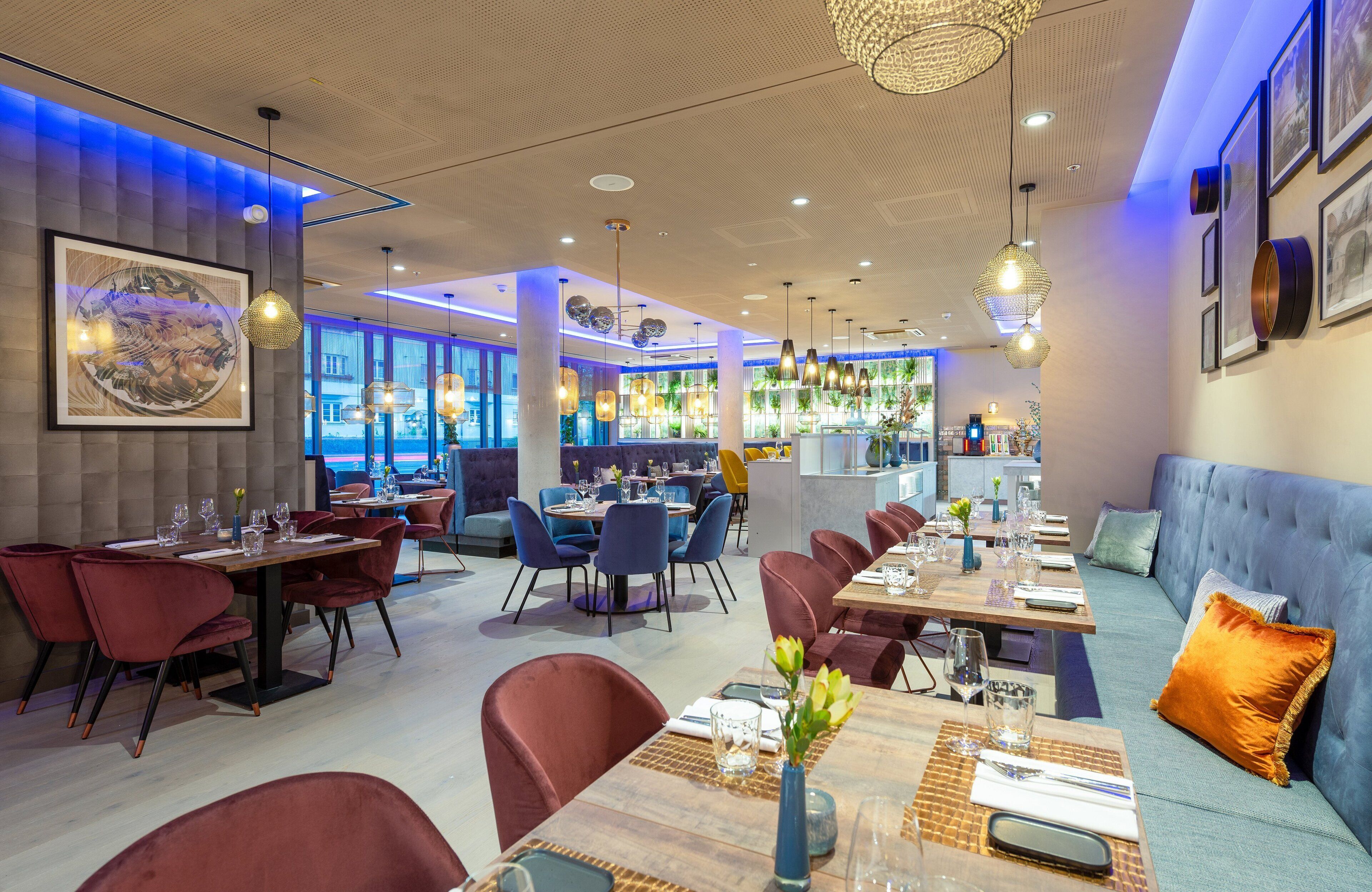 Un restaurante moderno con varias zonas de comedor, incluyendo una mesa común alargada y cabinas individuales.