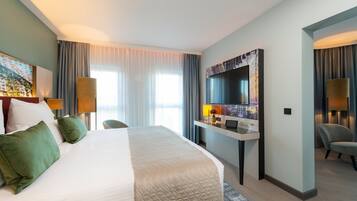 A hotel room with a large bed, a desk with a computer, a TV, and a chair.