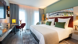 A hotel room with a large bed, a desk, a chair, and a TV. - Leonardo Hotel Augsburg (Augsburg)