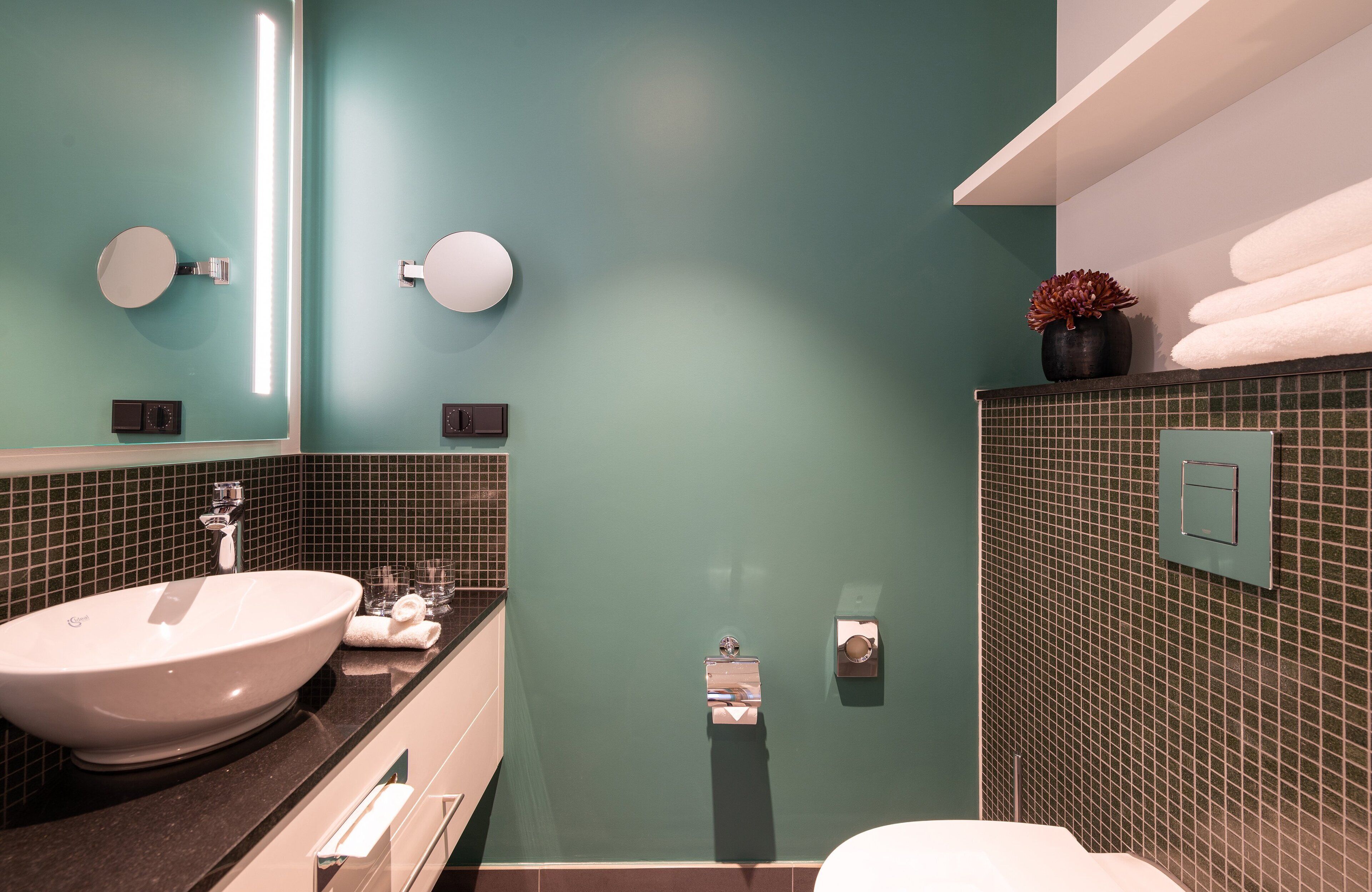 Un bagno con un lavabo a incasso, uno specchio, un porta asciugamani e un water.