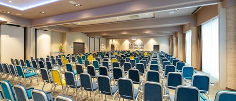 A conference room with rows of chairs, a carpeted floor, and a large screen at the front.