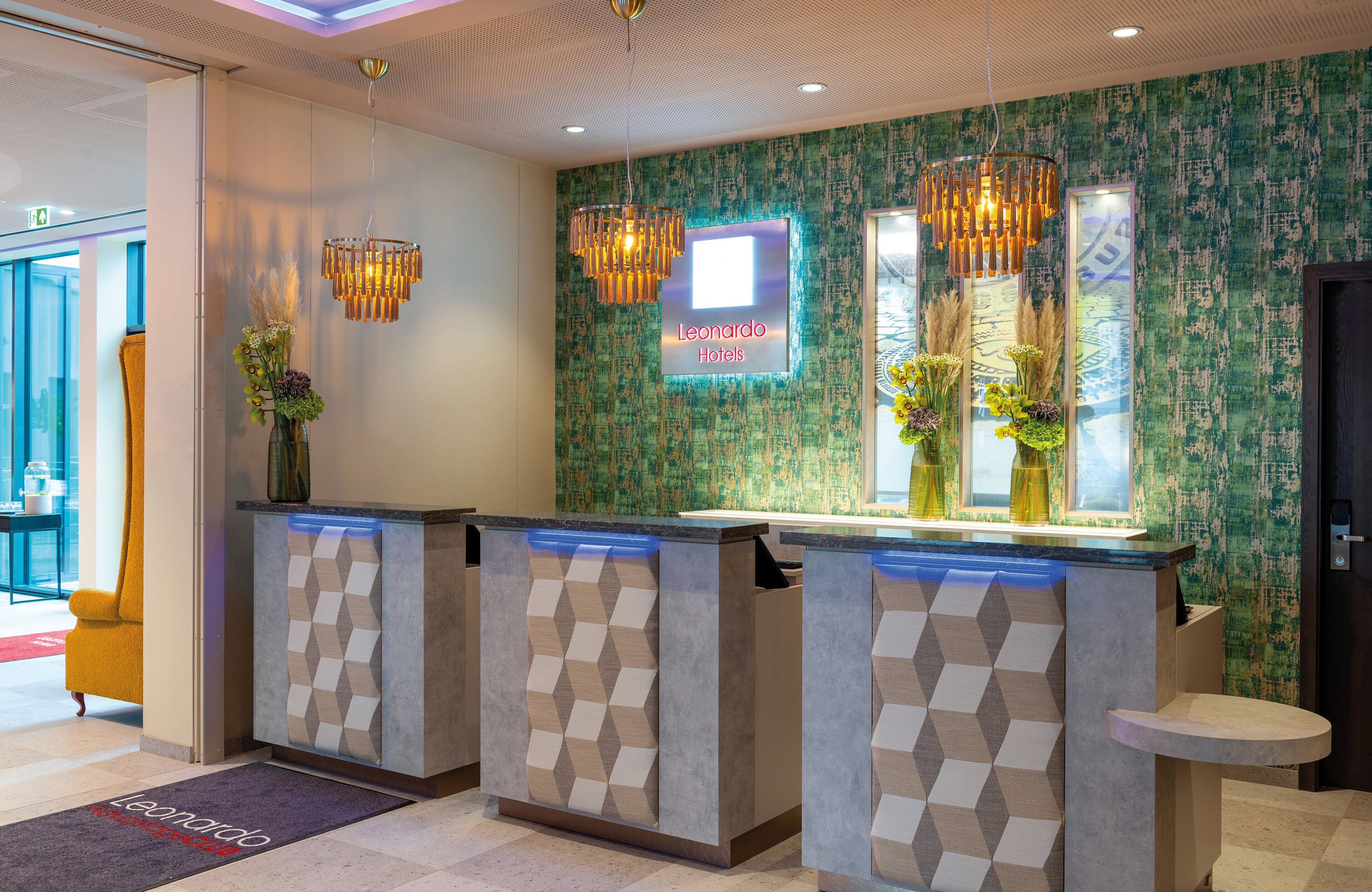A hotel reception area with a modern design, featuring a reception desk, a neon sign, and decorative lighting.