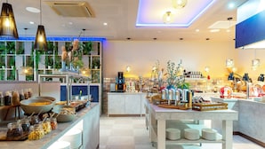 A modern hotel lobby with a buffet area, a coffee station, and a bar. - Leonardo Hotel Augsburg (Augsburg)