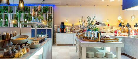 A modern hotel lobby with a buffet area, a coffee station, and a bar.