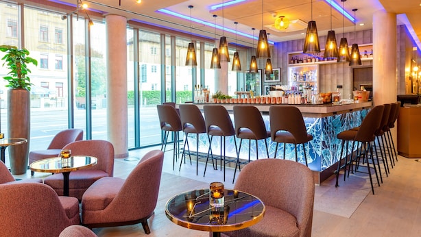 A modern bar area with multiple seating options, a bar counter, and pendant lighting. - Leonardo Hotel Augsburg (Augsburg)