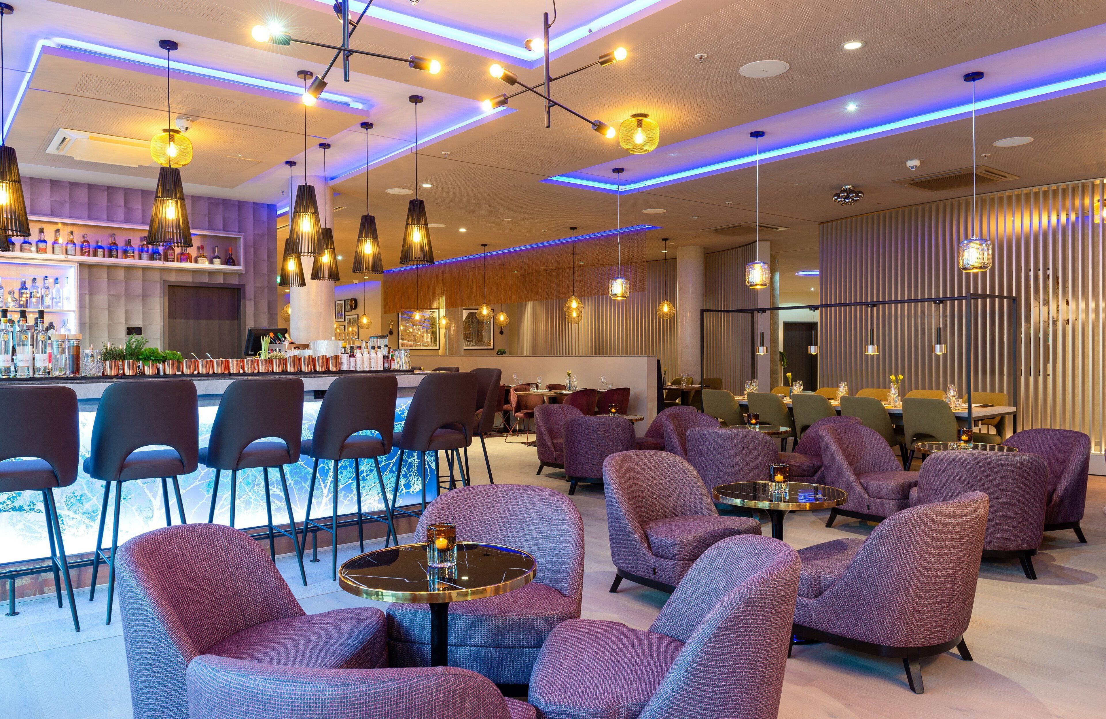 A modern bar area with seating and pendant lighting.