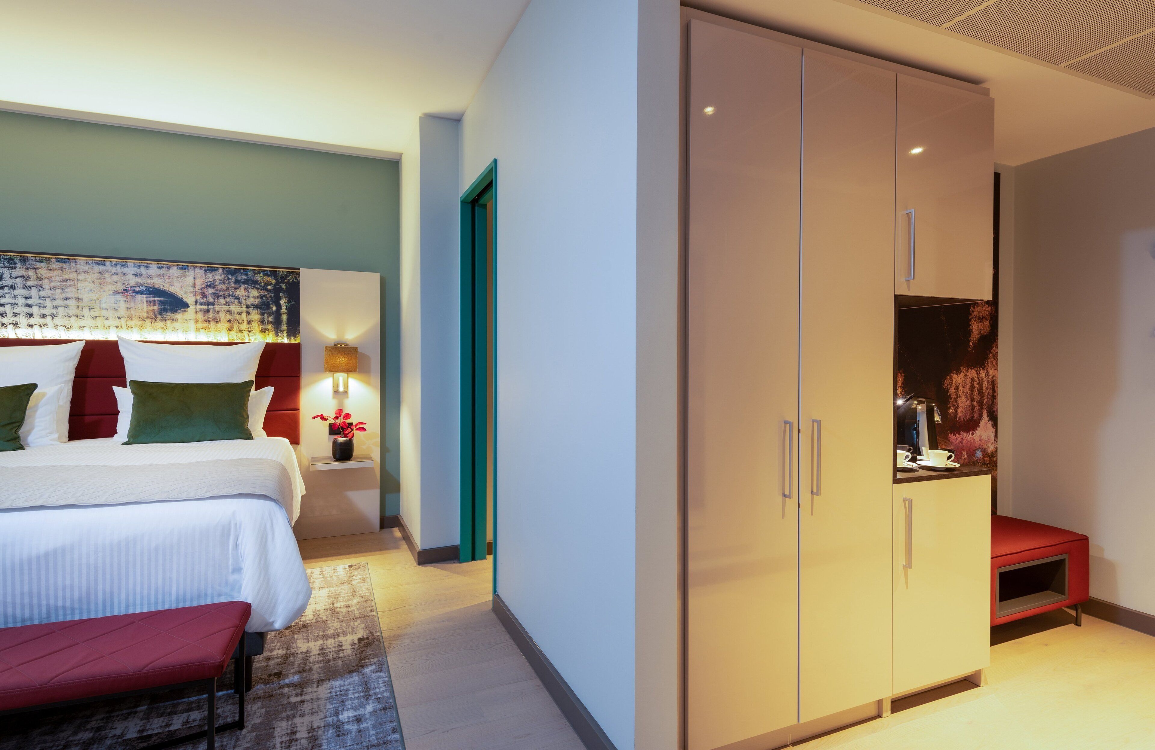 Una habitación de hotel con cama, mesita de noche, lámpara y armario.