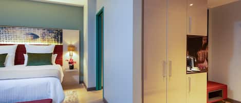 Una habitación de hotel con cama, mesita de noche, lámpara y armario.