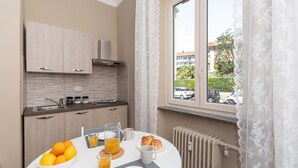 A modern kitchen with a dining table set for breakfast, including oranges, juice, and croissants.