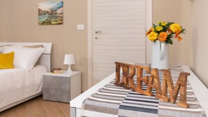 A neatly arranged bedroom with a bed, bedside table, lamp, and a wall-mounted painting.