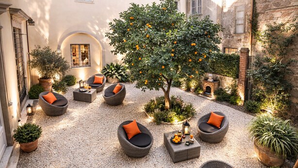 A courtyard with outdoor seating, a tree with oranges, and a stone wall. - Luxury Design Apartment in Central Lucca (Lucca)