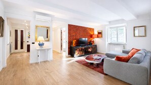 A modern living room with a grey sofa, a red accent wall, and a flat-screen TV on a black entertainment unit. - Luxury Design Apartment in Central Lucca (Lucca)