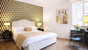 A hotel room with a large bed, two bedside tables with lamps, a modern chair, and a painting on the wall. - Luxury Design Apartment in Central Lucca (Lucca)