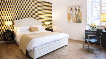 A hotel room with a large bed, two bedside tables with lamps, a modern chair, and a painting on the wall.