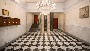 A grand hallway with a checkered marble floor, a large chandelier, and a staircase leading to another room. - Luxury Design Apartment in Central Lucca (Lucca)
