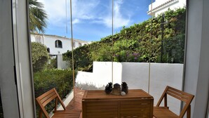 A wooden table and two chairs on a balcony with a view of a white building and greenery. - Riviera Del Sol Walking Distance to Beach -  Aldea (Mijas Costa)
