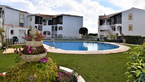 A pool surrounded by a well-maintained lawn, with a multi-story building featuring balconies and a tiled roof in the background. - Riviera Del Sol Walking Distance to Beach -  Aldea (Mijas Costa)