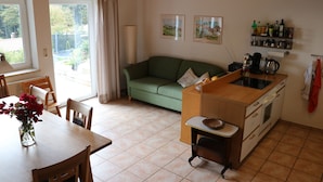 Un espacio habitable funcional con mesa de comedor, sofá, kitchenette y vistas al exterior.